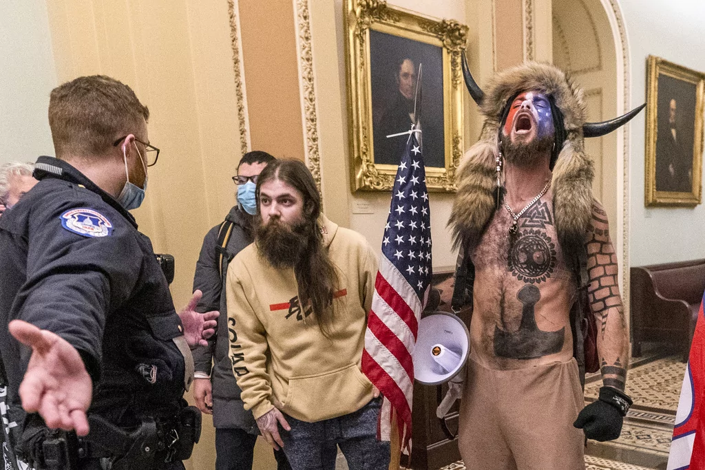 FILE - FILE - In this Jan. 6, 2021 file photo, supporters of President Donald Trump, including Jacob Chansley, right with fur hat, are confronted by U.S. Capitol Police officers outside the Senate Chamber inside the Capitol in Washington. On Friday, March 10, 2023, The Associated Press reported on stories circulating online incorrectly claiming footage from the Jan. 6, 2021, attack on the U.S. Capitol shows that Chansley was “led through the Capitol by police the entire time he was in the building.” (AP Photo/Manuel Balce Ceneta, File)