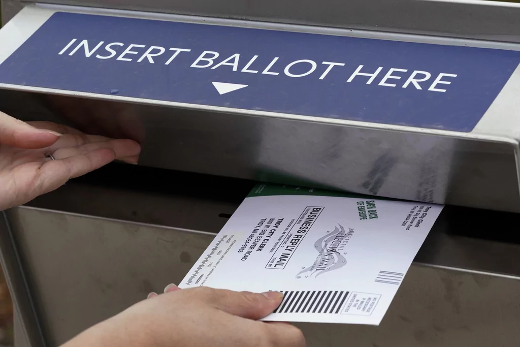 A Michigan voter inserts her absentee voter ballot into a drop box in Troy, Michigan, on Oct. 15, 2020. (AP Photo/Paul Sancya)