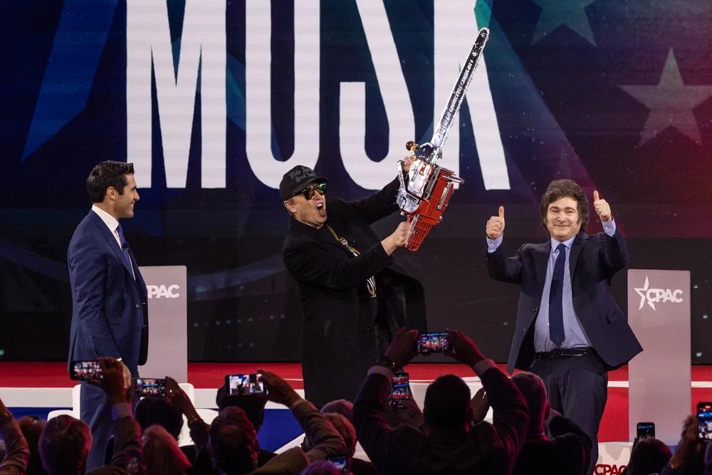 Tech billionaire Elon Musk holds a chainsaw onstage at CPAC.