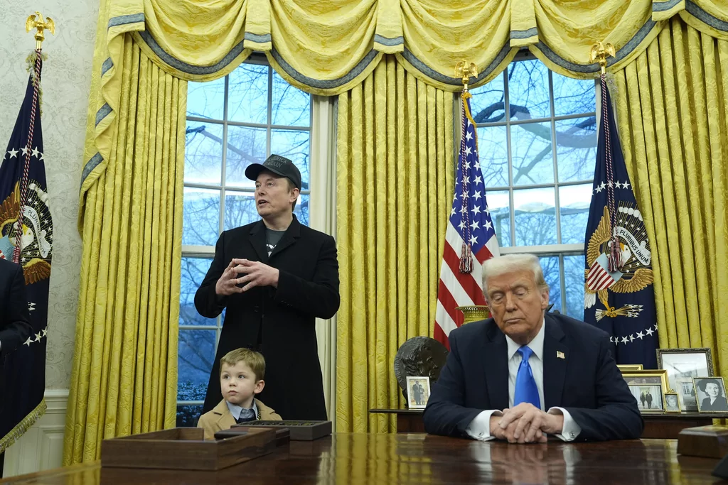 President Donald Trump listens as Elon Musk, joined by his son X Æ A-Xii, speaks in the Oval Office at the White House, Tuesday, Feb. 11, 2025, in Washington. (AP Photo/Alex Brandon)