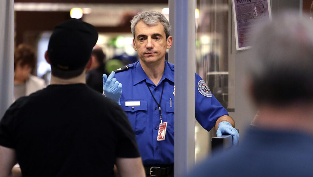 A TSA officer motions a traveler through at a security screening area during a partial federal government shutdown.