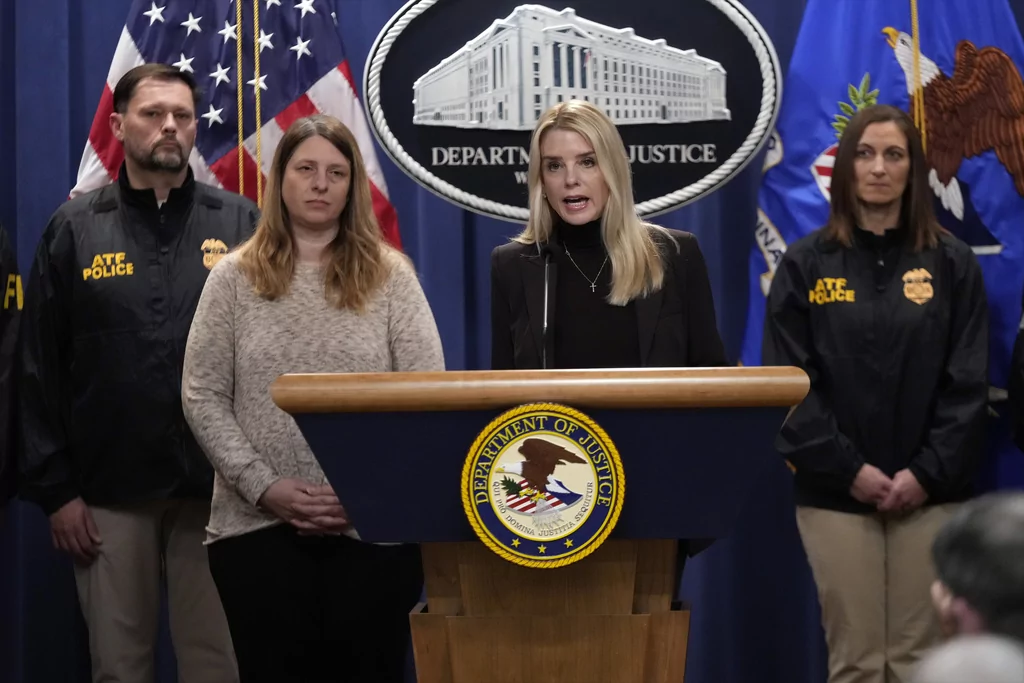 Attorney General Pam Bondi speaks at a news conference regarding immigration enforcement at the Justice Department, Wednesday, Feb. 12, 2025, in Washington, as Tammy Nobles, second from left, mother of Kayla Hamilton listens. (AP Photo/Ben Curtis)