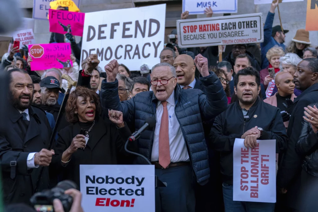 Senate Minority Leader Chuck Schumer (D-NY), accompanied by other members of congress, including Rep. Maxine Waters (D-CA), left, speaks during a rally against Elon Musk outside the Treasury Department in Washington, Tuesday, Feb. 4, 2025.