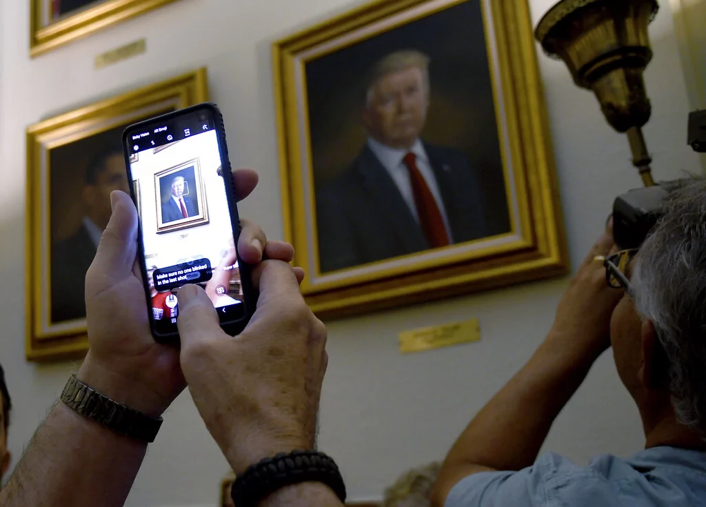 People take photos of President Donald Trump's portrait hanging in the Colorado Capitol after an unveiling ceremony Thursday, Aug. 1, 2019, in Denver. Colorado Republicans raised more than $10,000 through a GoFundMe account to commission the portrait, which was painted by Sarah Boardman, an artist who also produced the Capitol's portrait of President Barack Obama.