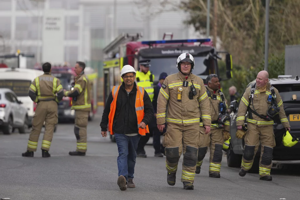 Firefighters wait at the area around the North Hyde electrical substation, which caught fire Thursday night and lead to a closure of Heathrow Airport in London, Friday, March 21, 2025.