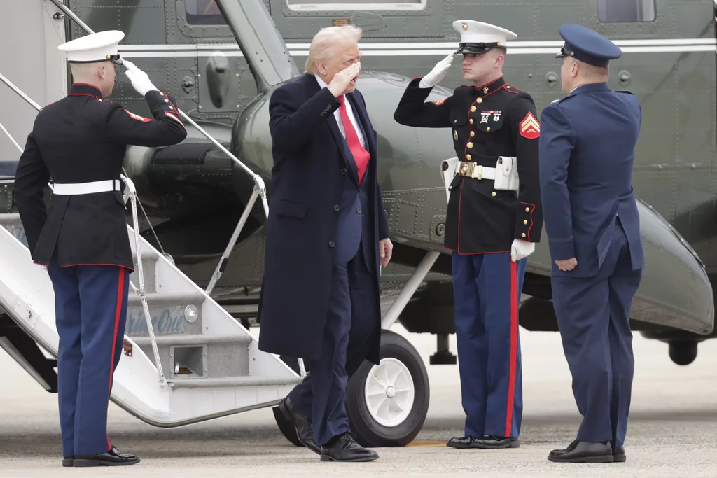 President Donald Trump, second from left, is greeted by Col. Paul Pawluk, Vice Commander of the 89th Airlift Wing, right, as he walks from Marine One before boarding Air Force One, Friday, March 14, 2025, at Joint Base Andrews, Md. 