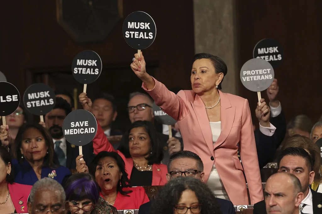 Rep. Nydia Velazquez, D-N.Y., holds a protest sign with fellow Democrats as President Donald Trump addresses a joint session of Congress at the Capitol in Washington, Tuesday, March 4, 2025. 