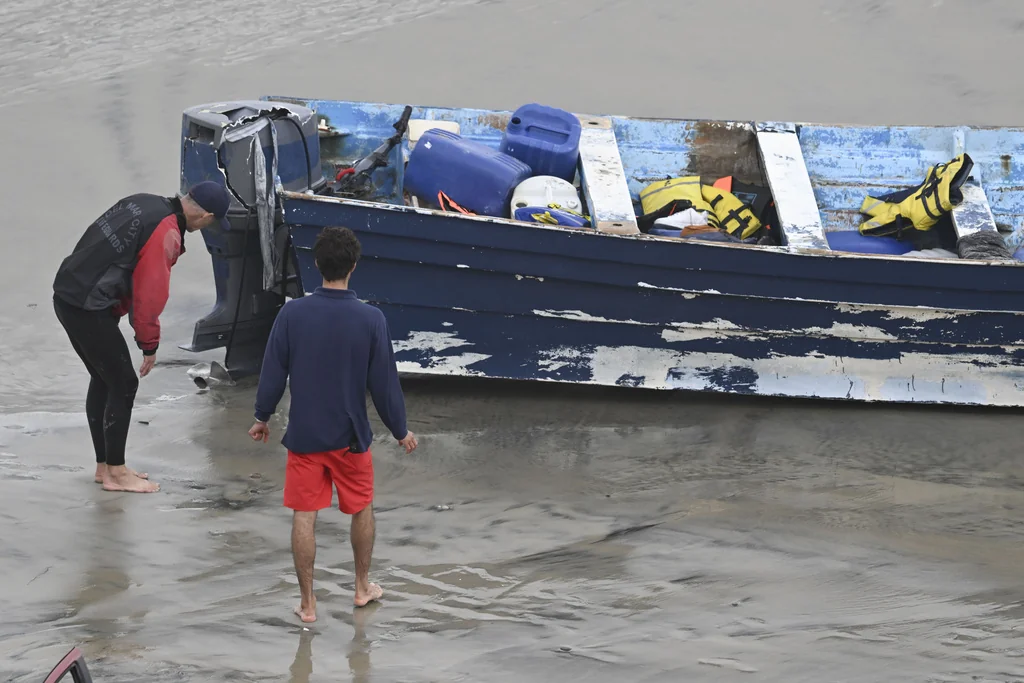 Del Mar lifeguards looks over a capsized boat on the beach Monday, May 5, 2025, in at Torrey Pines State beach in San Diego, Calif.