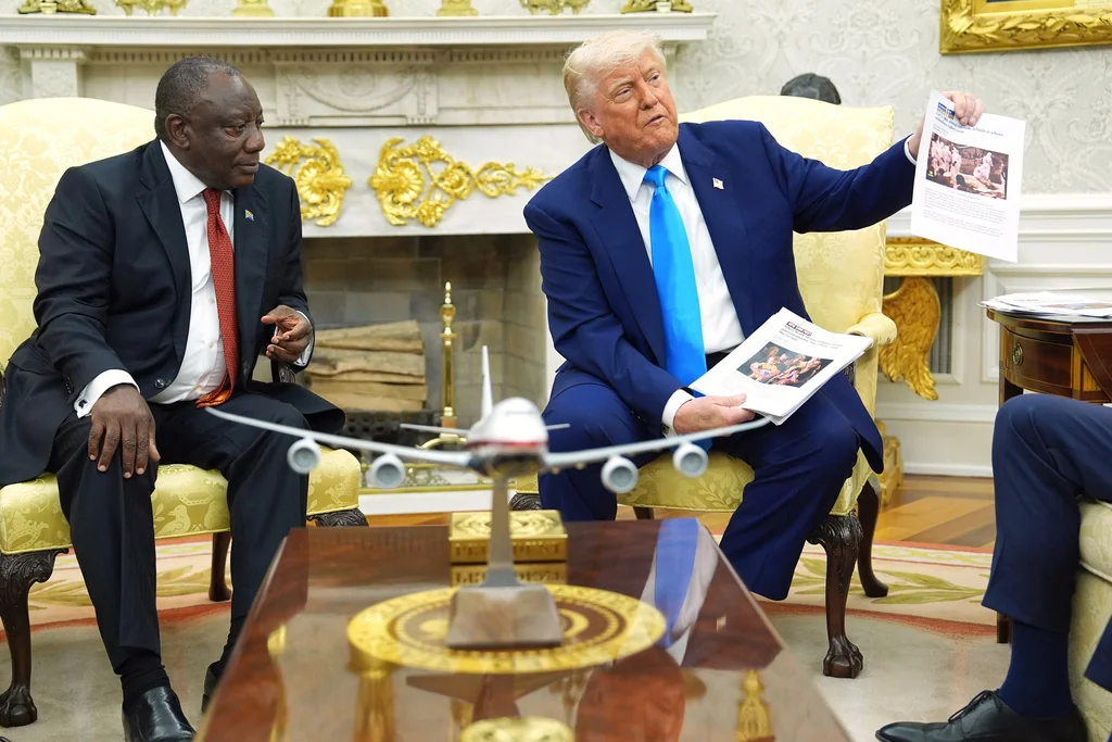 President Donald Trump shows documents as he meets South Africa's President Cyril Ramaphosa in the Oval Office of the White House, Wednesday, May 21, 2025, in Washington. (AP Photo/Evan Vucci)