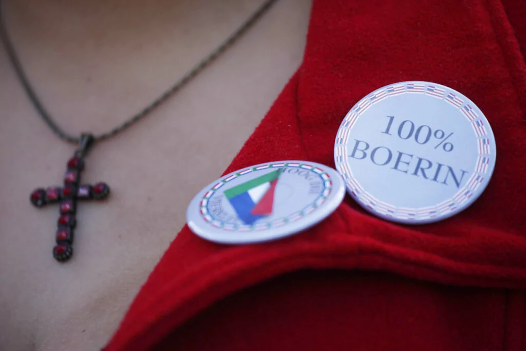 A Boer woman with a pin saying "100% Boer woman" outside a courthouse in Ventersdrop, 140 km West of Johannesburg, South Africa, Tuesday April 6, 2010. (AP Photo/Jerome Delay)