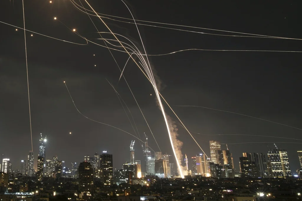 A projectile hit buildings as Israeli Iron Dome air defense system fires to intercept missiles over Tel Aviv, Israel, Friday, June 13, 2025.