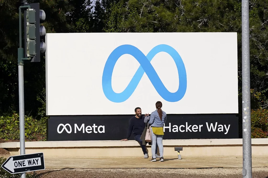 People talk near a Meta sign outside of the company's headquarters in Menlo Park, California, March 7, 2023. Meta's Oversight Board said Monday, Feb. 5, 2024, that it is urging the company to clarify its approach to manipulated media so its platforms can better beat back the expected flood of online election disinformation this year. The recommendations come after the board reviewed an altered video of President Joe Biden that was misleading but didn't violate the company's policies. (AP Photo/Jeff Chiu)
