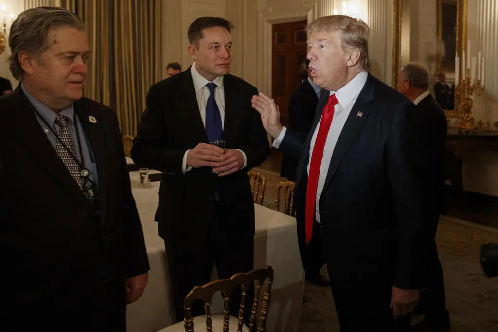 President Donald Trump talks with Tesla and SpaceX CEO Elon Musk, center, and White House chief strategist Steve Bannon during a meeting with business leaders in the State Dining Room of the White House in Washington, Friday, Feb. 3, 2017.