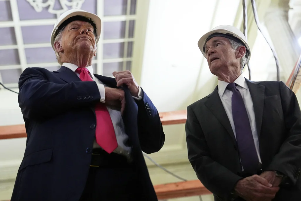 President Donald Trump, left, reaches for a document of cost figures as Federal Reserve Chairman Jerome Powell watches during a visit to the Federal Reserve, Thursday, July 24, 2025, in Washington.