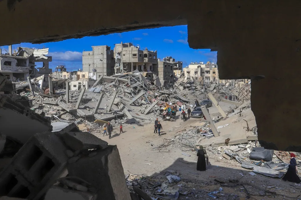 Palestinians walk through the rubble caused by the Israeli air and ground offensive in Rafah, southern Gaza Strip, Monday, Jan. 20, 2025.