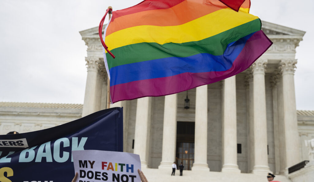 Supporters of the LGBT wave their flag in front of the U.S. Supreme Court, Tuesday, Oct. 8, 2019, in Washington. The Supreme Court is set to hear arguments in its first cases on LGBT rights since the retirement of Justice Anthony Kennedy. Kennedy was a voice for gay rights while his successor, Brett Kavanaugh, is regarded as more conservative.