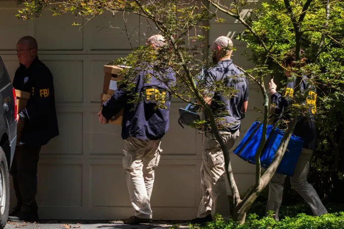FBI agents carry bags and boxes out of former national security adviser John Bolton's house Friday, Aug. 22, 2025, in Bethesda, Md. (AP Photo/Manuel Balce Ceneta)