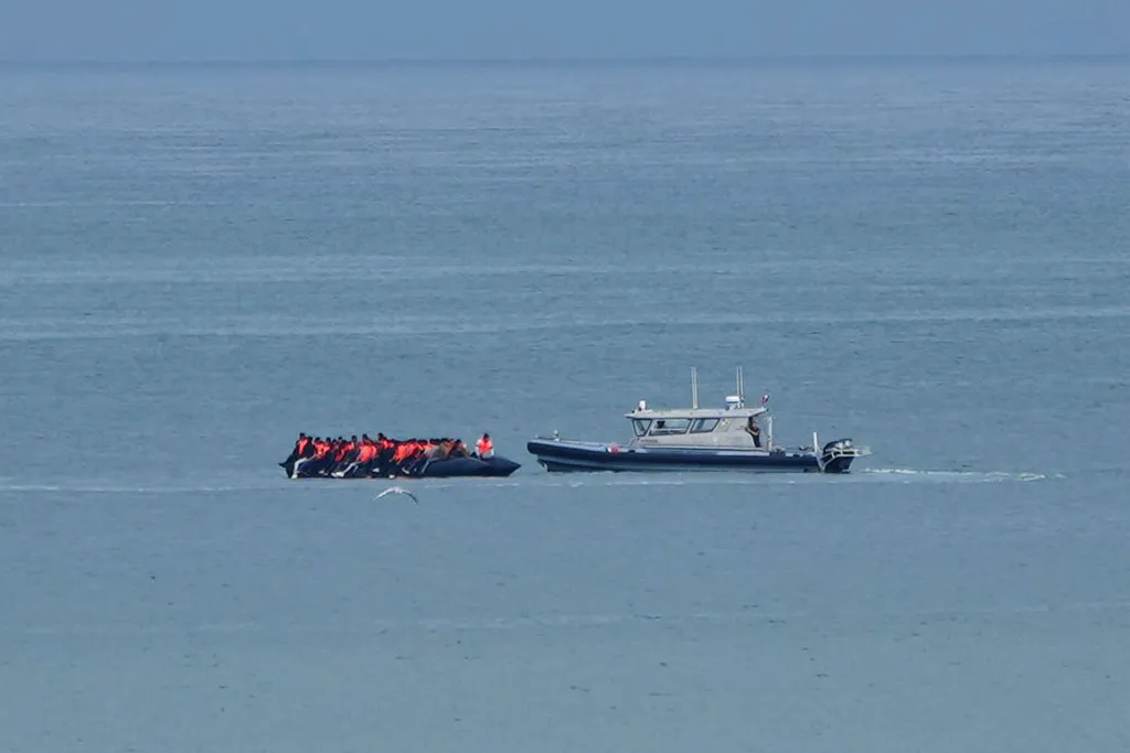 A boat thought to be carrying migrants is escorted by a vessel from the French Gendarmerie Nationale in the English Channel.