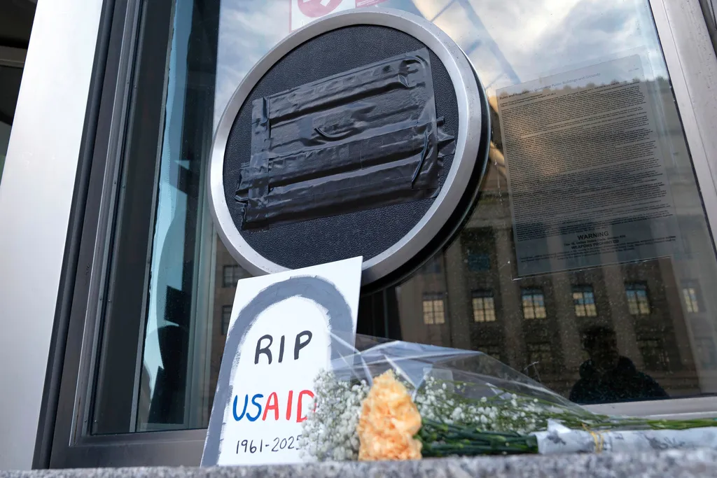 Flowers and a sign are placed outside the headquarters of the U.S. Agency for International Development.