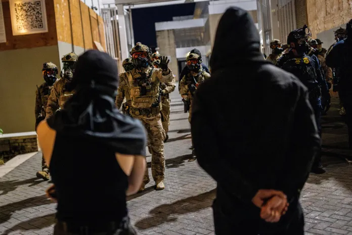 Federal law enforcement officers clear protesters from a driveway outside a United States Immigration and Customs Enforcement (ICE) facility.