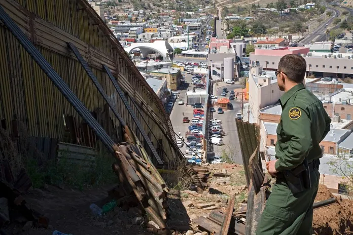 Nogales, Arizona, US Border Patrol agent Michael Scioli stands by the border fence that separates the United States and Mexico on a hill above Nogales. Mexico is on the left, and the USA on the right. The debris in the foreground is left over from patching numerous holes cut in the fence by people crossing the border illegally. (Photo by: Jim West/UCG/Universal Images Group via Getty Images)
