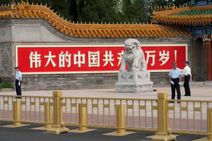 Chinese security personnel stand guard near a sign that reads "Long Live the Great Chinese Communist Party."