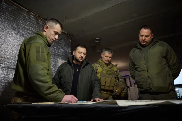 Zelensky looks over war map with Ukrainian officials.
