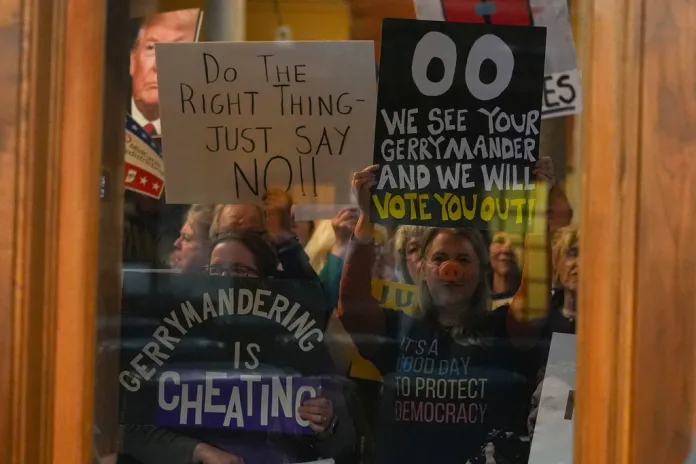 Protesters are seen through a window in the Senate Chamber during dissuasion before a vote to redistrict the state's congressional map, Thursday, Dec. 11, 2025, at the Statehouse in Indianapolis. (AP Photo/Michael Conroy)