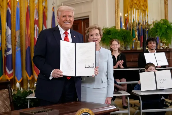 President Donald Trump holds up a signed executive order alongside Secretary of Education Linda McMahon in the East Room of the White House in Washington, Thursday, March 20, 2025.
