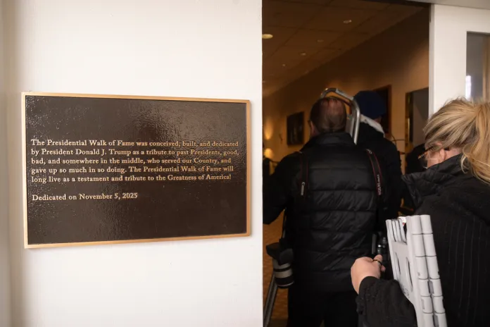 Members of the press walk past a plaque on the "Presidential Walk of Fame" at the White House.