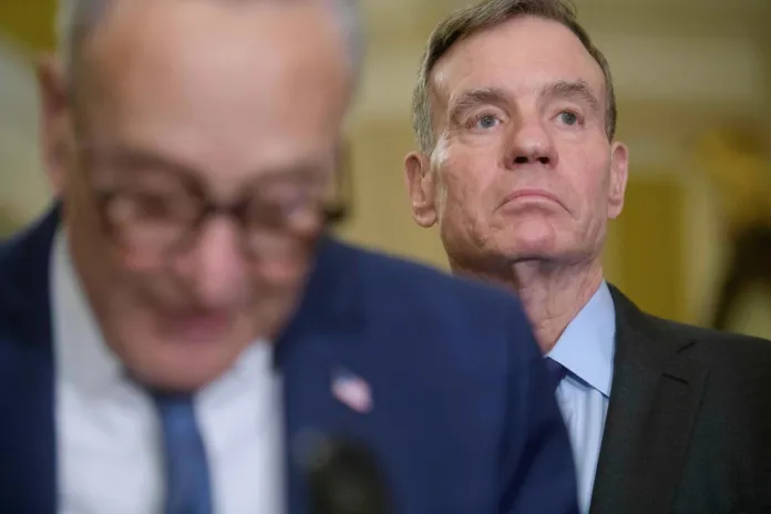 Sen. Mark Warner, D-Va., right, listens as Senate Minority Leader Chuck Schumer, D-N.Y., left, speaks during the Senate Democrat policy luncheon news conference at the Capitol, Tuesday, Jan. 6, 2026, in Washington