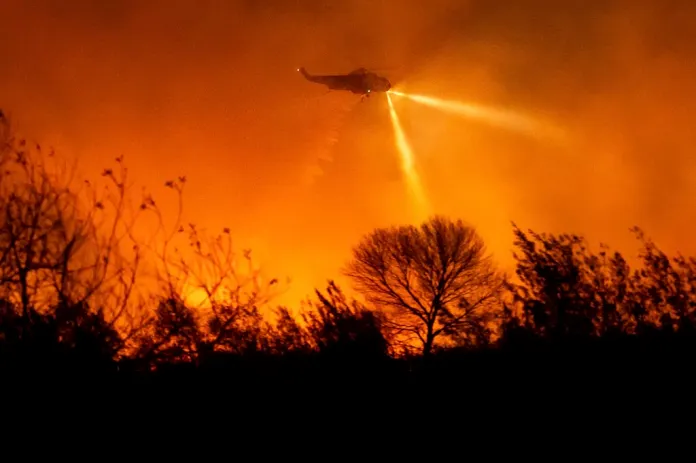 A helicopter drops water while fighting the Auto fire in Ventura County, California, Monday, Jan. 13, 2025. (AP Photo/Noah Berger)
