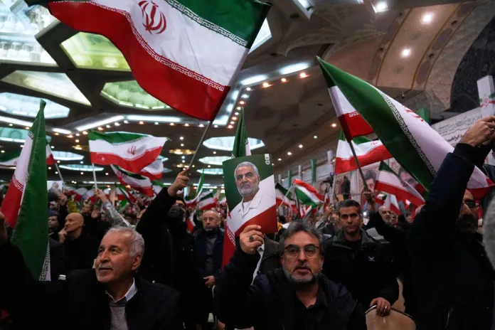 Iranians wave flags and carry portraits of deceased IRGC commander Qassem Soleimani