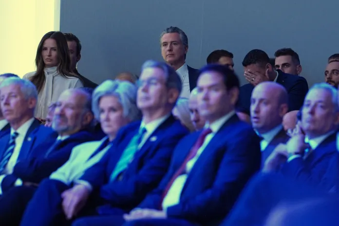 California Governor Gavin Newsom, center rear, listens to the address of President Donald Trump during the Annual Meeting of the World Economic Forum in Davos, Switzerland, Wednesday, Jan. 21, 2026.