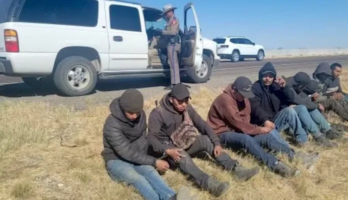 A group of migrants sit on the side of a road near Van Horn, Texas, after being found inside a smuggler's vehicle this week.