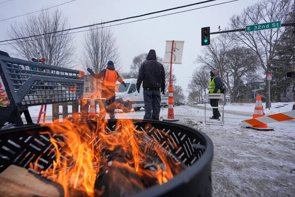 People stand near a blockade set up to deter federal immigration enforcement vehicles in Minneapolis.