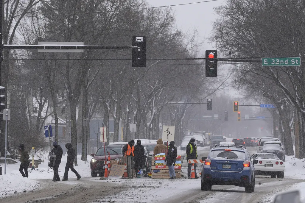 People stand near a blockade set up to deter federal immigration enforcement vehicles in Minneapolis.