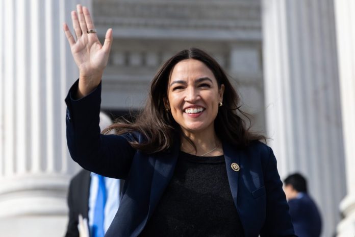 Rep. Alexandria Ocasio-Cortez waving as she walks down the Capitol steps.