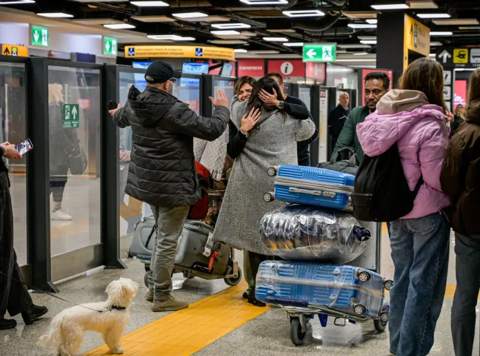 Italian passengers embrace after returning from Abu Dhabi
