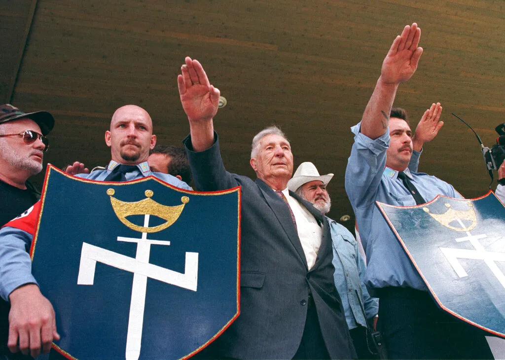 FILE - In this July 3, 1999 file photo, Richard Butler, center, founder of the Aryan Nations sect, salutes along with other members of the neo Nazi group during a rally in Coeur d' Alene, Idaho. The Aryan Nations is long gone from northern Idaho, but its reputation lingers to the chagrin of locals. (AP Photo/Jeff T. Green)