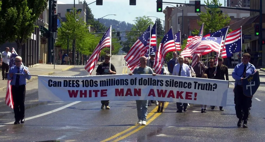 FILE - In this July 3, 1999 file photo, Richard Butler, center, founder of the Aryan Nations sect, salutes along with other members of the neo Nazi group during a rally in Coeur d' Alene, Idaho. The Aryan Nations is long gone from northern Idaho, but its reputation lingers to the chagrin of locals. (AP Photo/Jeff T. Green)