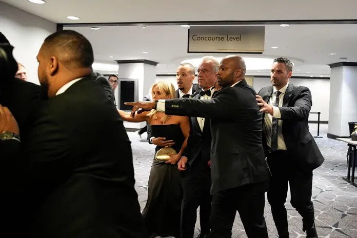 Law enforcement officers surround Robert F. Kennedy Jr., US secretary of Health and Human Services (HHS), and his wife, actress Cheryl Hines following reports of a shooting during the White House Correspondents' Association (WHCA) dinner in Washington, DC, US on Saturday, April 25, 2026. President Donald Trump and Vice President JD Vance were evacuated from the White House Correspondents' Association dinner event in Washington Saturday following a security incident at the venue. Photographer: Yuri Gripas/Abaca/Bloomberg via Getty Images