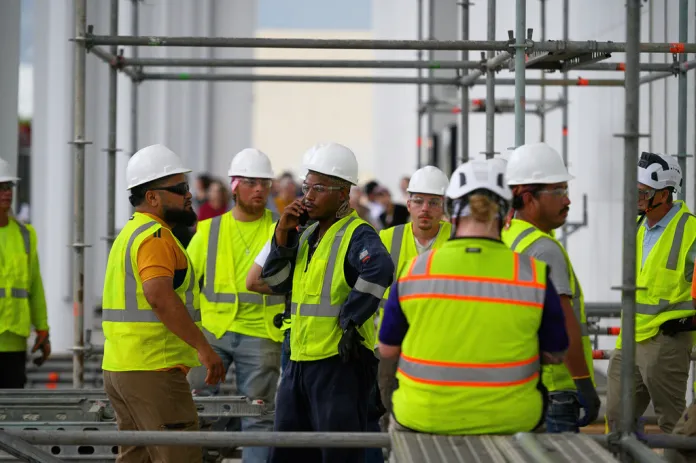 Workers wait for the rain to stop before resuming work to remove President Donald Trump's name from the John F. Kennedy Center for the Performing Arts in Washington, Friday, June 12, 2026.