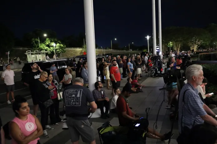 People wait for President Donald Trump's name to be removed from the John F. Kennedy Center for the Performing Arts in Washington, Friday, June 12, 2026. 